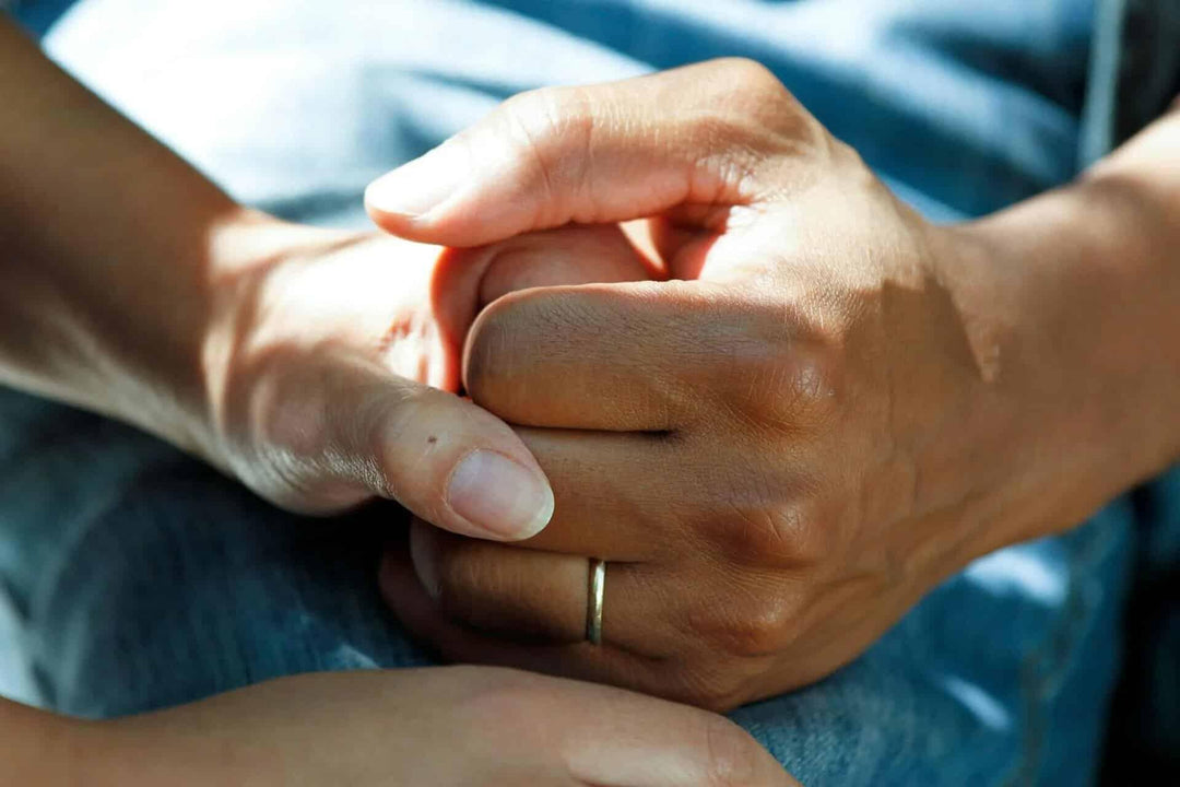 Close-up of two hands clasped in support, cancer patient care, emotional comfort