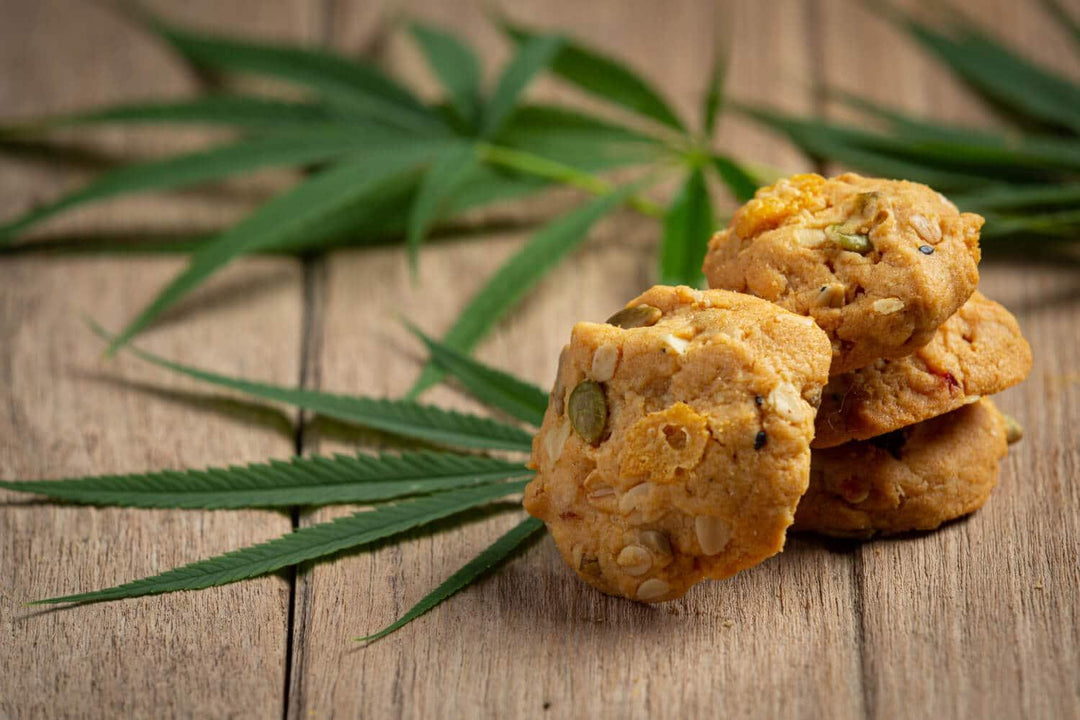 Homemade cannabis cookies stacked on wooden table with cannabis leaves in background