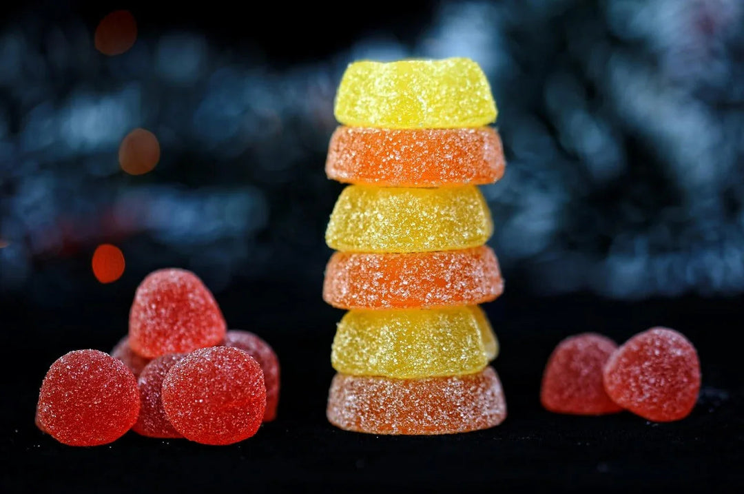 Assorted Delta-9 edibles, sugar-coated gummies stacked on black background