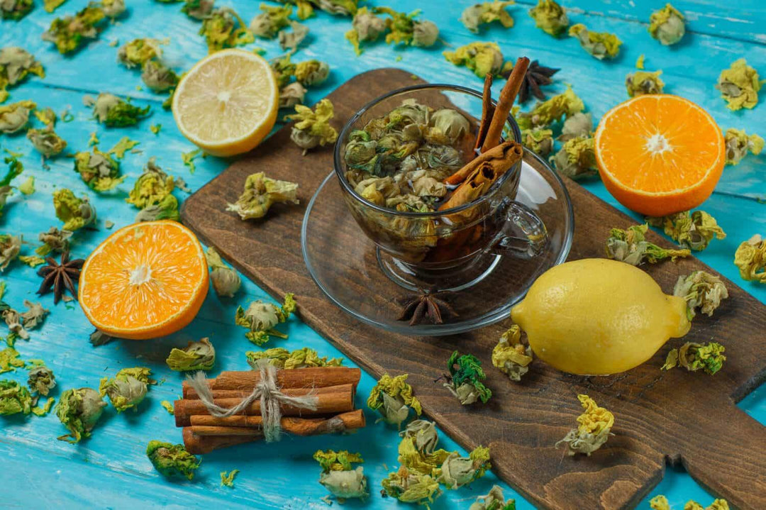 Herbal tea with cinnamon, lemon, orange, and dried buds on rustic blue table