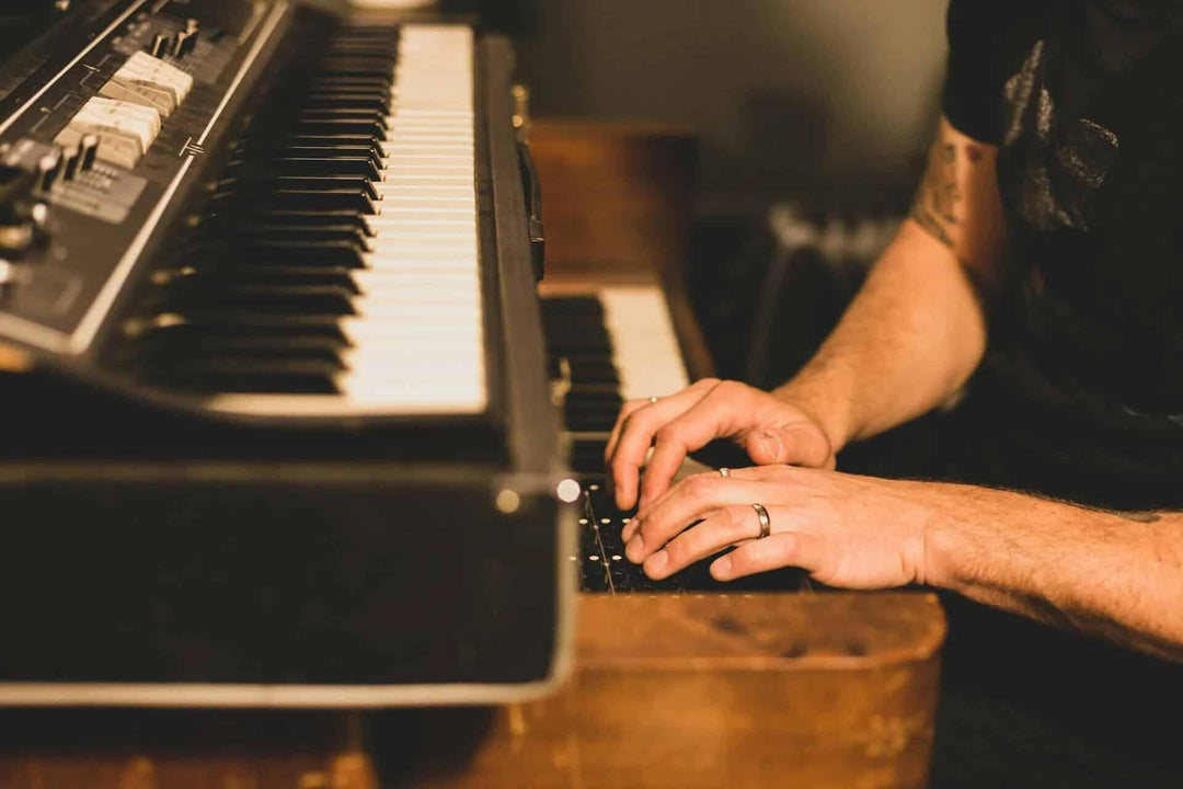 Musician playing vintage electric piano, close-up of hands and keyboard indoors