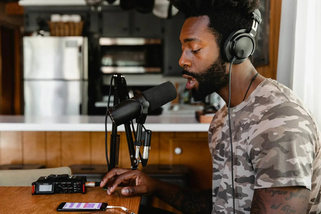 Man recording vocals with headphones and microphone in home studio kitchen setting