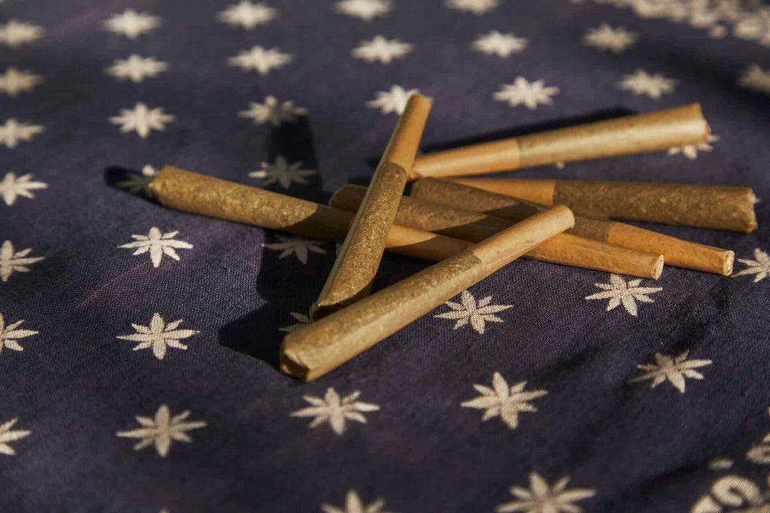 Pre rolled weed joints on blue cannabis leaf patterned cloth