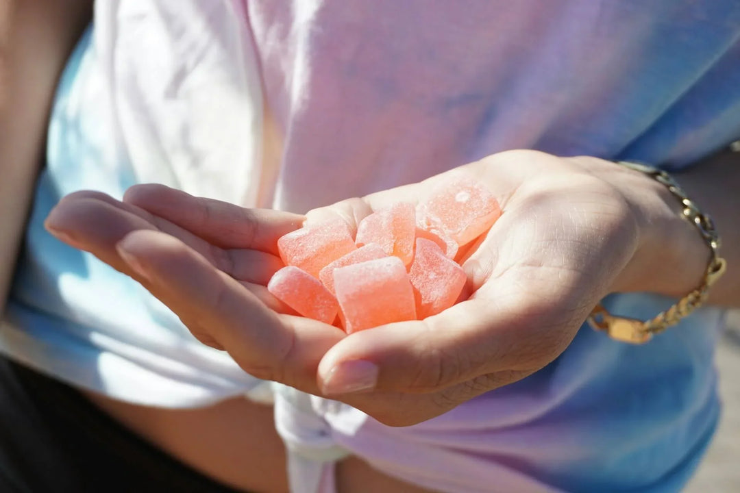 Hand holding pink sugar-coated gummies outdoors, THC gummies candy